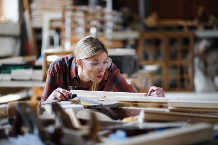 Carpenter measuring timber in her workshop
